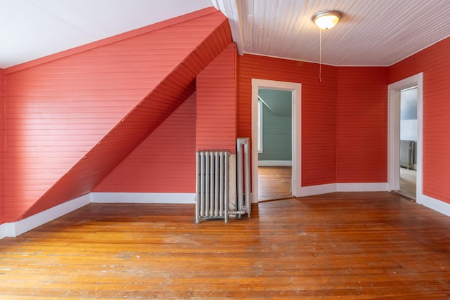 additional living space with radiator, baseboards, and wood finished floors