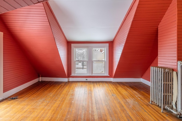 bonus room featuring baseboards, vaulted ceiling, radiator heating unit, and wood finished floors