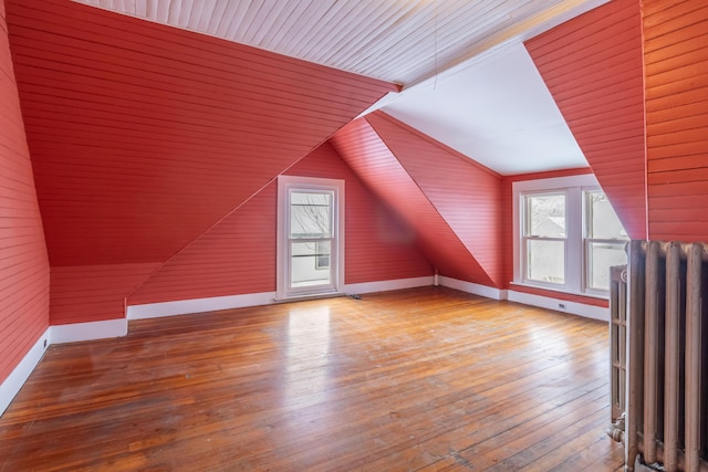 bonus room featuring lofted ceiling, a healthy amount of sunlight, radiator heating unit, and wood finished floors