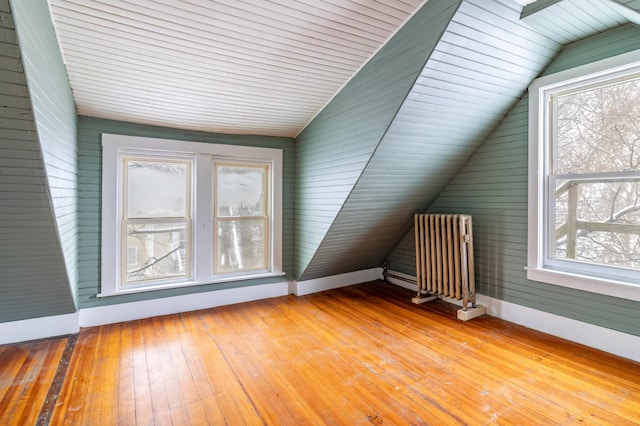 bonus room featuring vaulted ceiling, baseboards, light wood-style flooring, and radiator