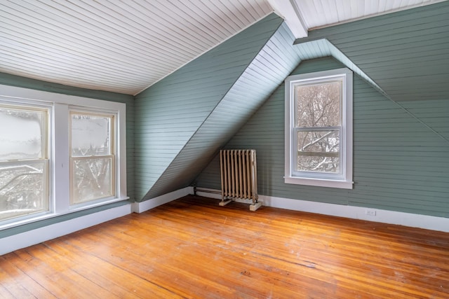 additional living space featuring radiator, light wood-style floors, baseboards, and vaulted ceiling