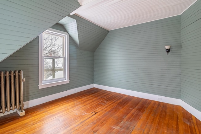 bonus room with light wood finished floors, radiator heating unit, baseboards, and vaulted ceiling