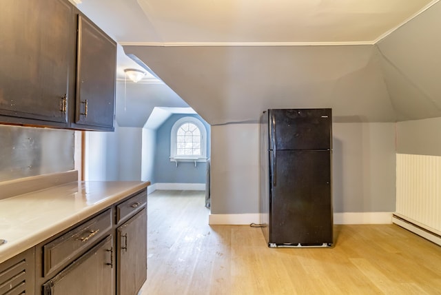 kitchen with light countertops, freestanding refrigerator, vaulted ceiling, light wood-type flooring, and baseboards