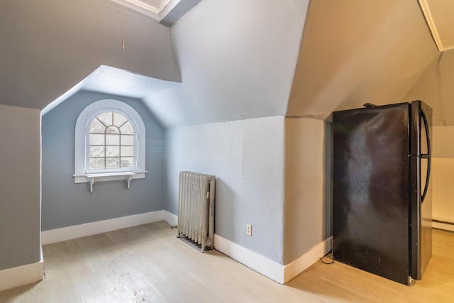 additional living space featuring lofted ceiling, baseboards, light wood-style flooring, and radiator