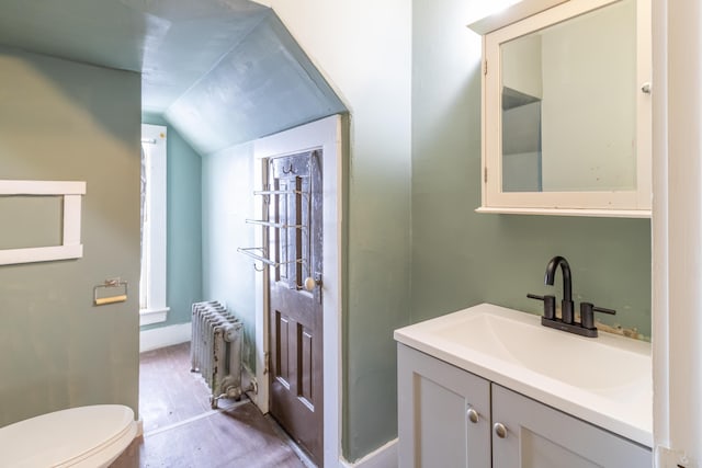 bathroom with lofted ceiling, radiator heating unit, toilet, and vanity