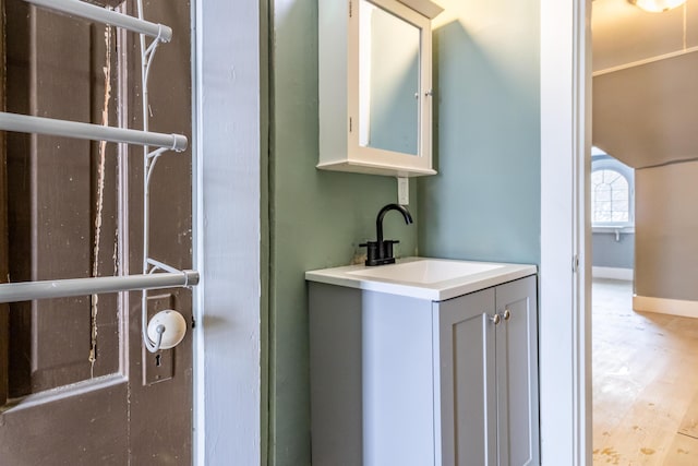 bathroom with wood finished floors, vanity, and baseboards