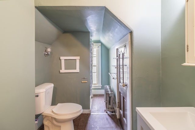 bathroom with lofted ceiling, baseboards, toilet, and radiator heating unit