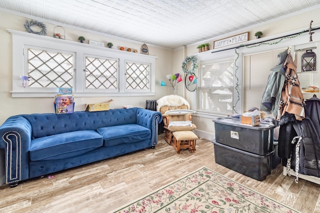 sitting room featuring ornamental molding, light wood finished floors, and baseboards