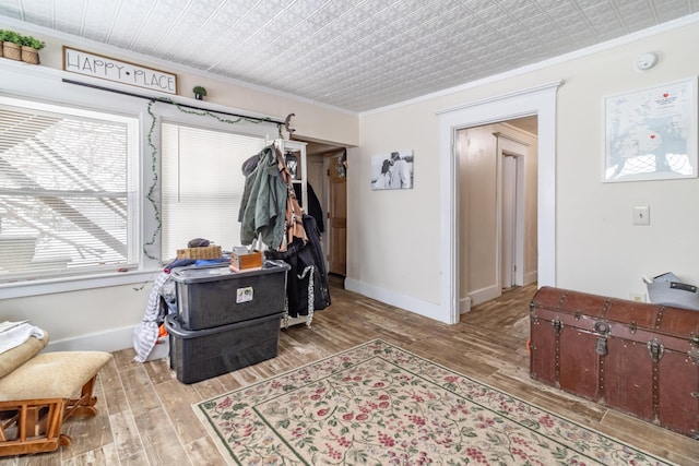 interior space featuring baseboards, ornamental molding, and light wood-style floors