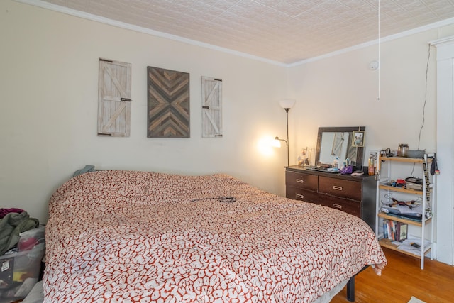 bedroom with ornamental molding and wood finished floors