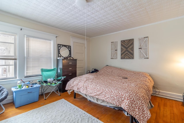 bedroom with ornamental molding, wood finished floors, and baseboards