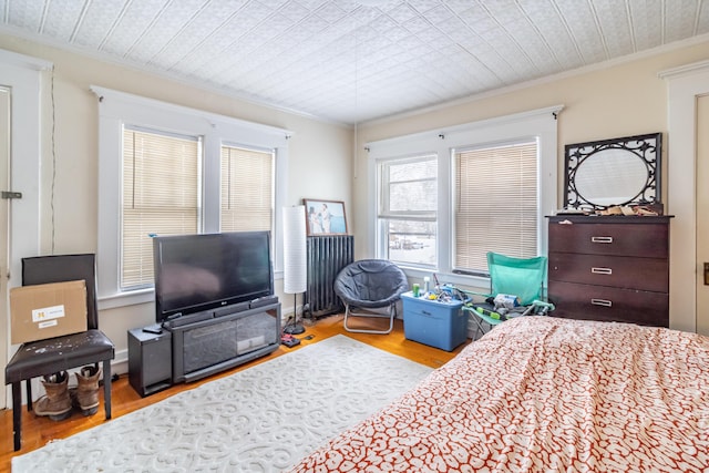 bedroom featuring ornamental molding and light wood finished floors