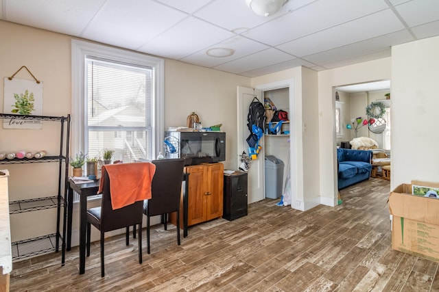 home office featuring a paneled ceiling, baseboards, and wood finished floors