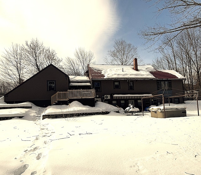 snow covered property with a hot tub and a wooden deck