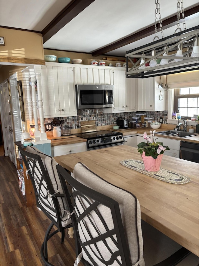 kitchen featuring tasteful backsplash, wooden counters, appliances with stainless steel finishes, and white cabinets