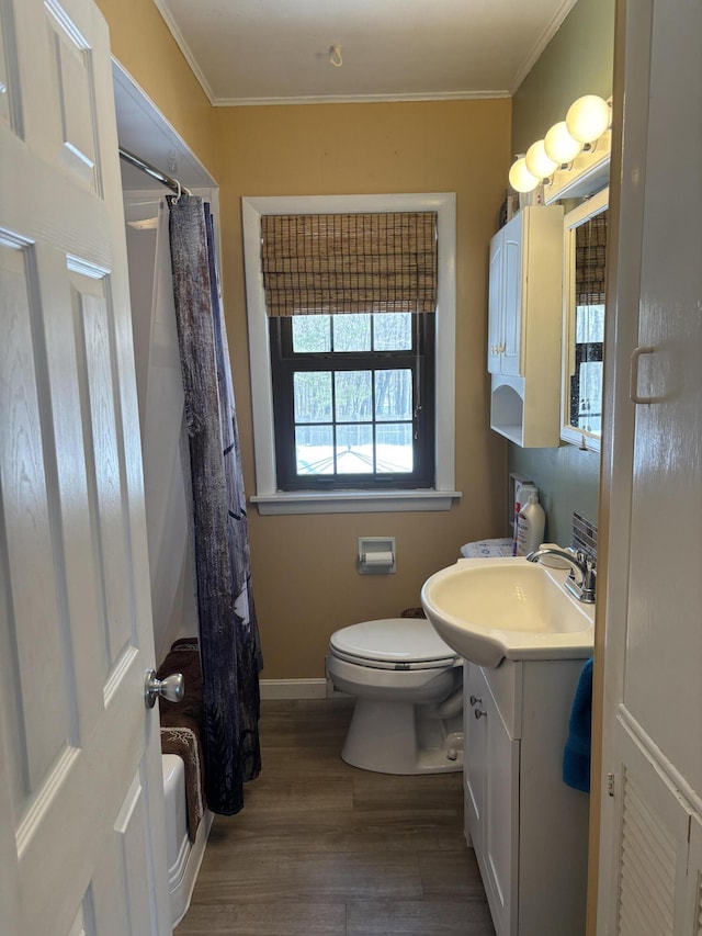 bathroom with toilet, wood finished floors, vanity, and crown molding