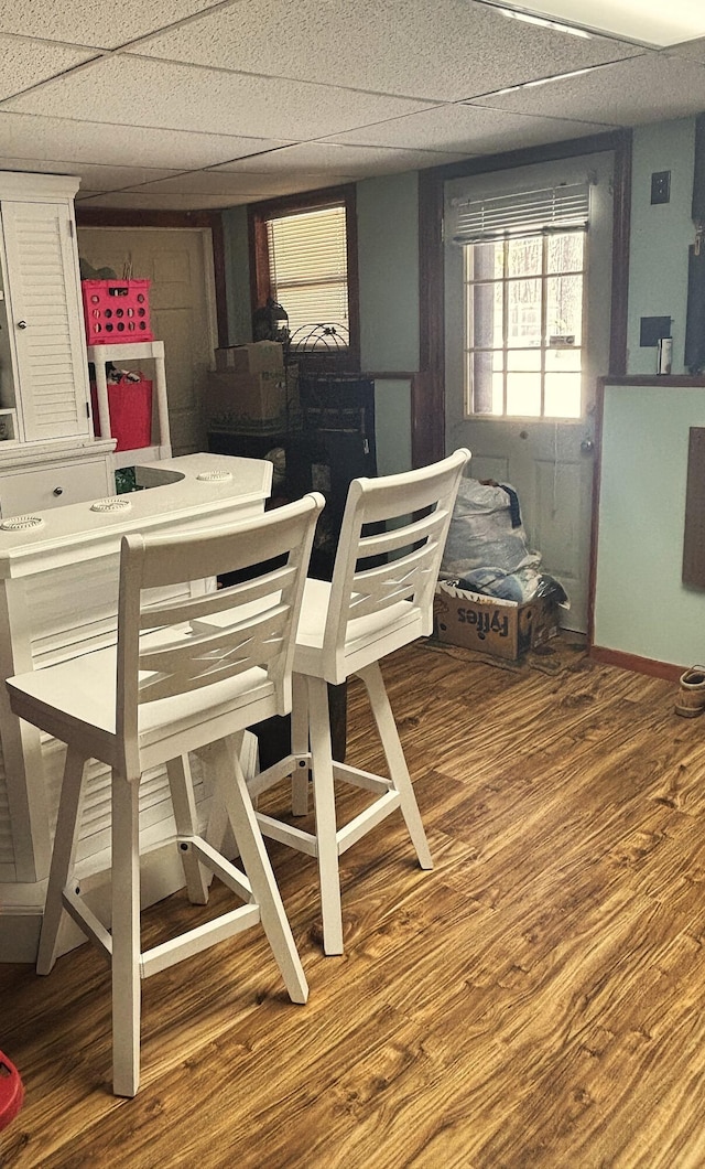 dining area with wood finished floors, a paneled ceiling, and baseboards