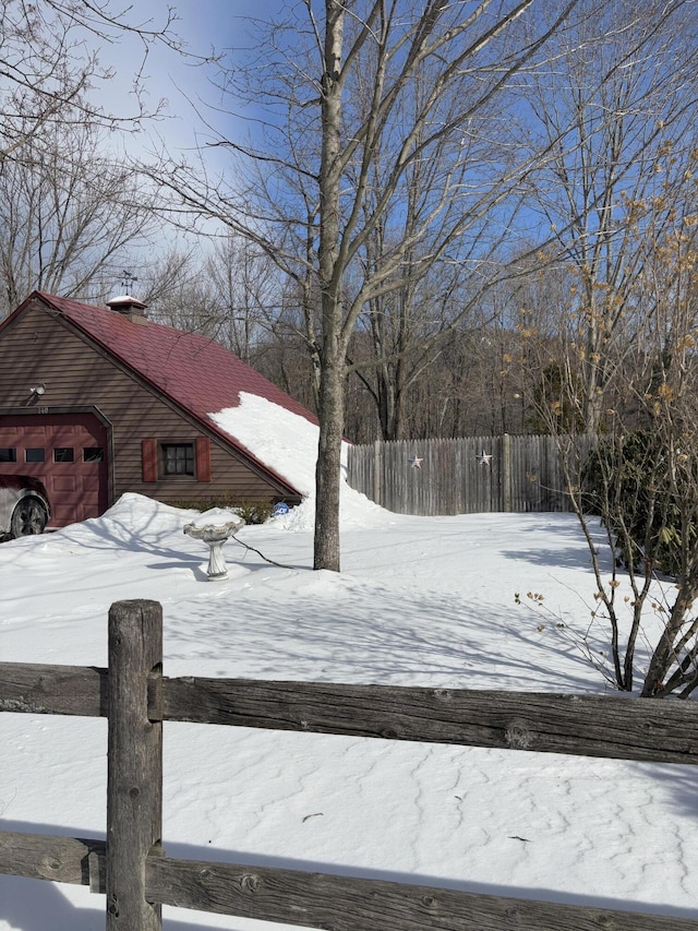 yard covered in snow with a garage and fence