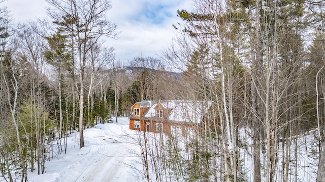 snowy aerial view featuring a wooded view