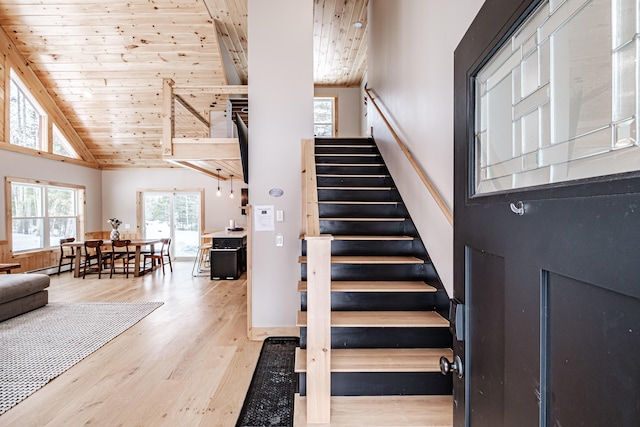 stairway with wood ceiling, high vaulted ceiling, and wood finished floors