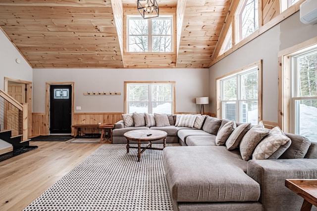 living area with plenty of natural light, wainscoting, a wall unit AC, and wooden ceiling