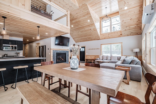 dining space with wooden ceiling, a fireplace, a towering ceiling, and light wood-style floors