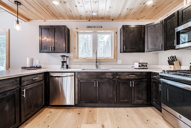 kitchen featuring stainless steel appliances, a sink, wood ceiling, light countertops, and light wood finished floors