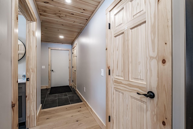 hallway featuring light wood finished floors, recessed lighting, wood ceiling, and baseboards