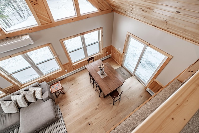 dining area featuring high vaulted ceiling, light wood-type flooring, wainscoting, and baseboard heating