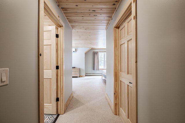 hallway with a baseboard heating unit, wood ceiling, light colored carpet, and baseboards