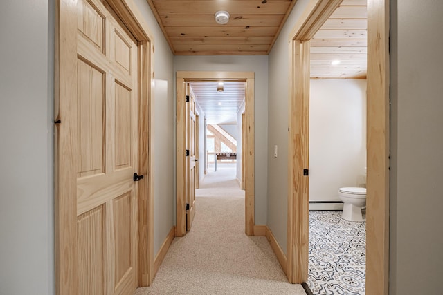 corridor with light carpet, baseboard heating, wooden ceiling, and baseboards