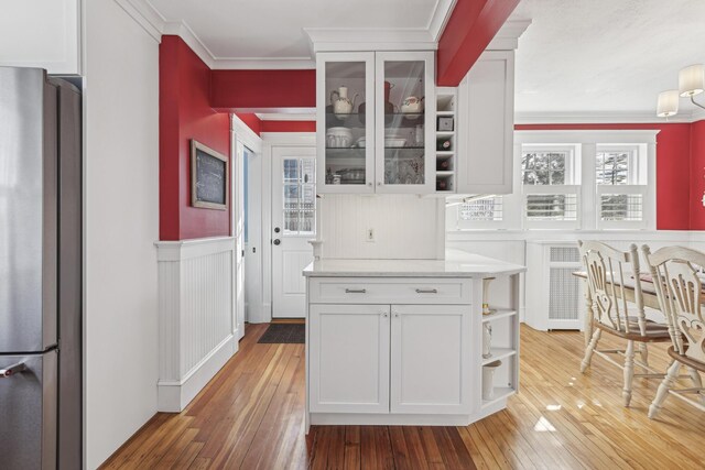 kitchen with ornamental molding, freestanding refrigerator, a wainscoted wall, and white cabinetry