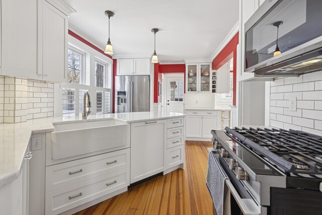 kitchen featuring stainless steel appliances, light wood-style flooring, a sink, and white cabinetry