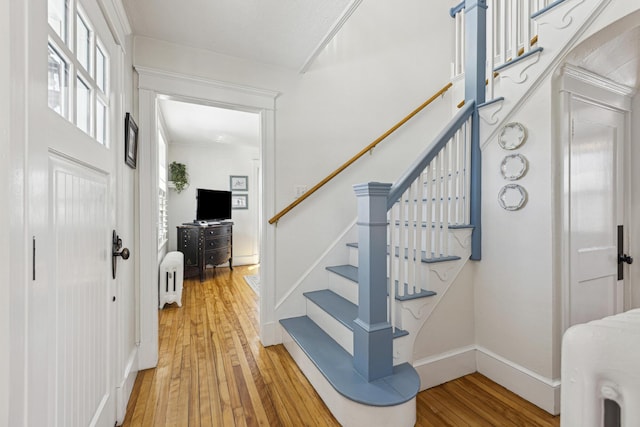 stairs featuring baseboards, hardwood / wood-style floors, and radiator