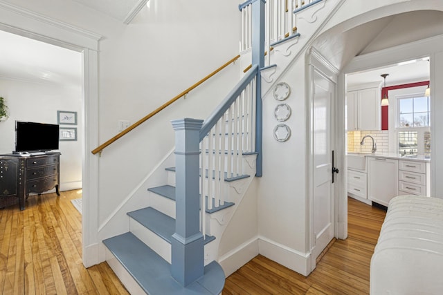 stairs featuring arched walkways, baseboards, and hardwood / wood-style floors