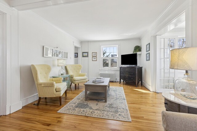 living area with hardwood / wood-style flooring, radiator heating unit, and crown molding