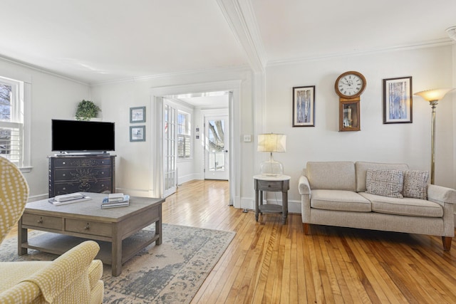 living area with light wood finished floors, ornamental molding, and baseboards