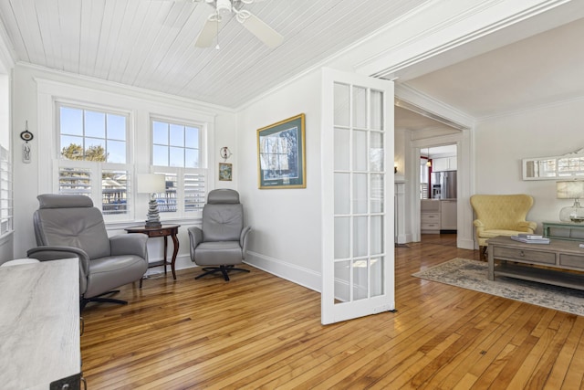 sitting room with a ceiling fan, baseboards, crown molding, and light wood finished floors