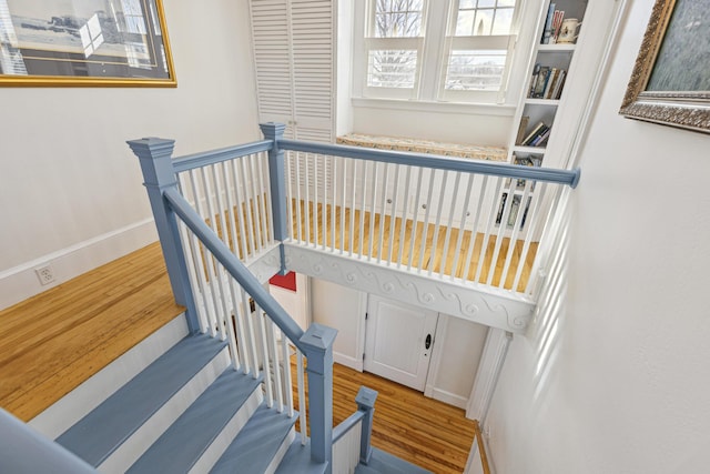 staircase with baseboards and wood finished floors