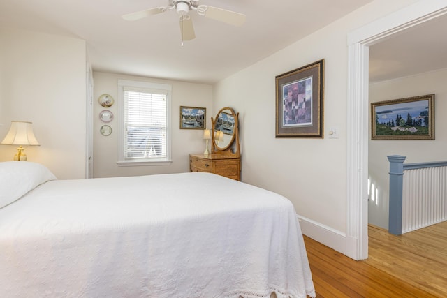 bedroom featuring wood finished floors, a ceiling fan, and baseboards