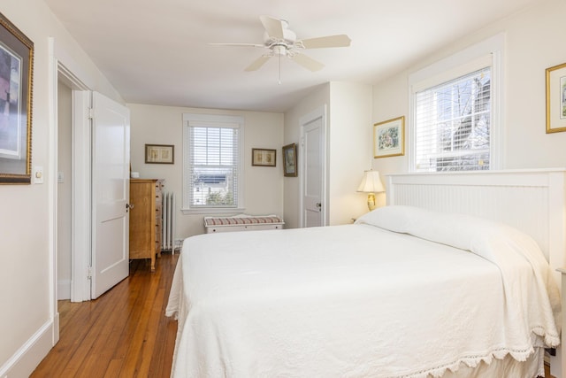 bedroom featuring ceiling fan, baseboards, radiator heating unit, and wood finished floors