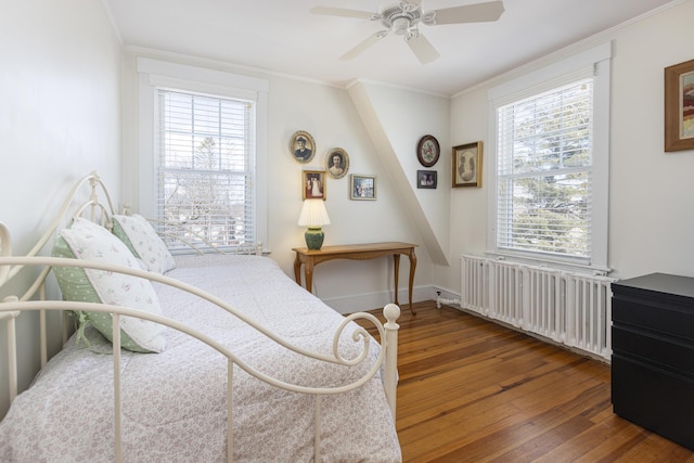 bedroom with hardwood / wood-style flooring, radiator heating unit, ceiling fan, and crown molding