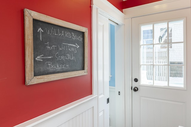 entryway with a wainscoted wall, a healthy amount of sunlight, and a decorative wall