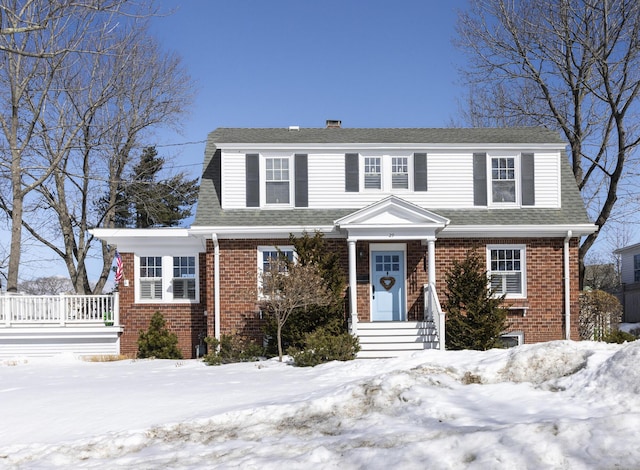 view of front of house featuring brick siding and roof with shingles