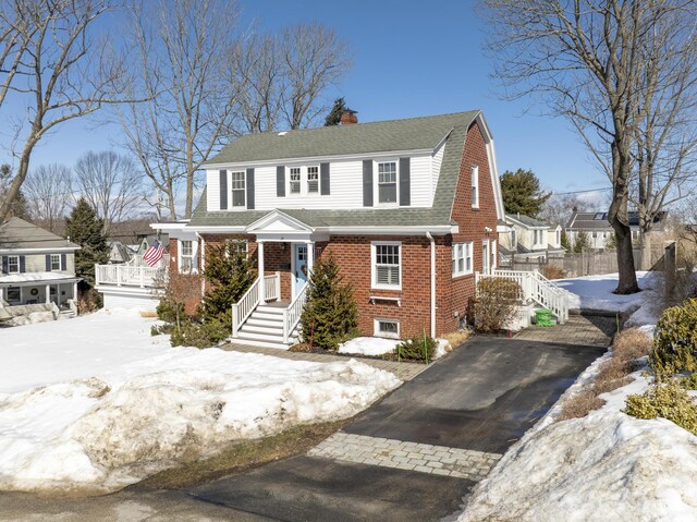 dutch colonial with aphalt driveway, brick siding, a shingled roof, a gambrel roof, and a chimney