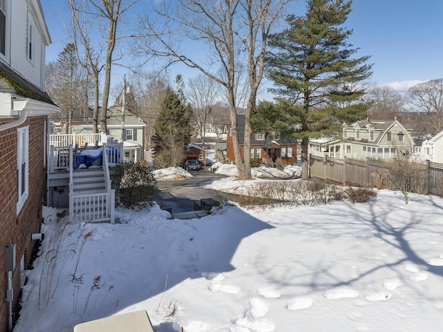 yard covered in snow featuring a residential view, fence, and stairs