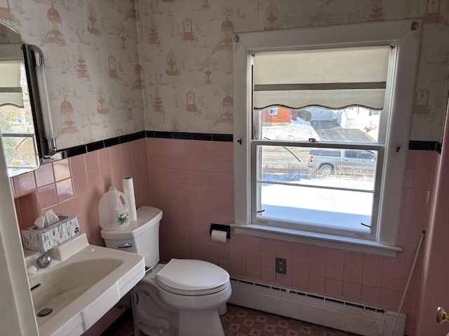 bathroom featuring wallpapered walls, wainscoting, toilet, a baseboard radiator, and a sink