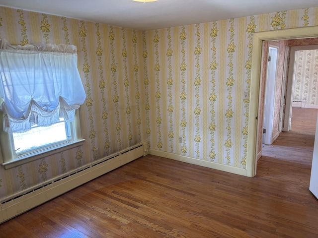 spare room with baseboards, baseboard heating, wood finished floors, and wallpapered walls