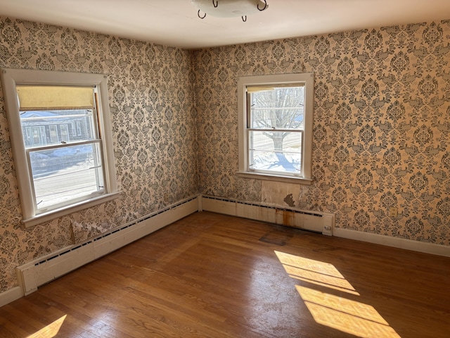 empty room with wallpapered walls, wood finished floors, and baseboards