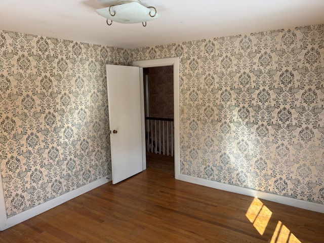 unfurnished room with wood finished floors and wallpapered walls